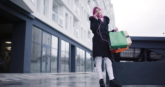 Girl models stylish outfits while shopping in an urban area on a rainy day, capturing vibrant moments and modern lifestyle