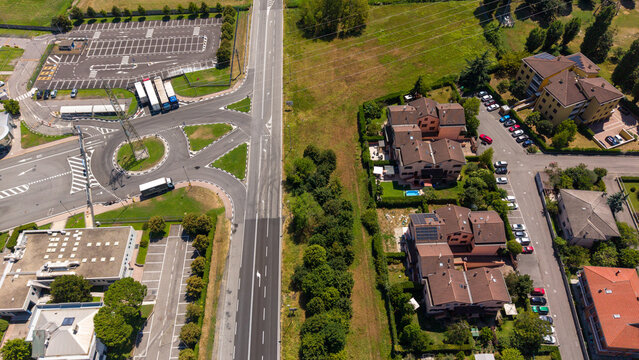 Aerial View of Urban Intersection: An overhead perspective captures a bustling intersection with a roundabout, roads, buildings, houses, and parked cars. Bellaria, Peschiera Borromeo, Italy
