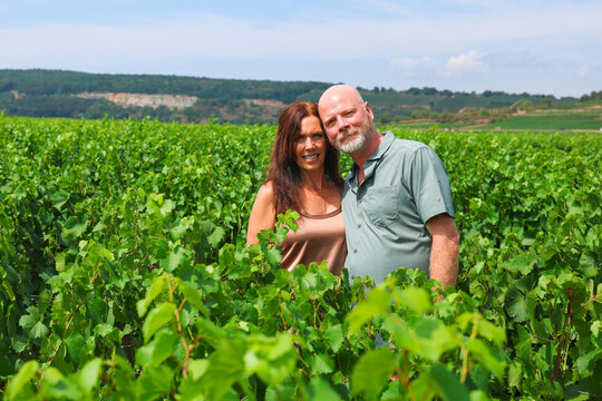 Couple standing together in Burgundy vineyards, enjoying summer travel, wine culture, nature, and scenic countryside surroundings.