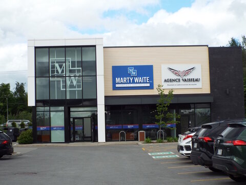 Gatineau, Quebec, Canada &ndash; June 13, 2026: A modern commercial building exterior features bilingual signage for "Marty Waite courtiers immobiliers and Agence Vaisseau" near parked cars on Chem. Vanier.