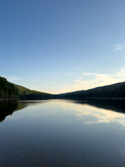 Naklejka premium Scenic View of Serene Mountain Lake Under Clear Sky and Soft Clouds