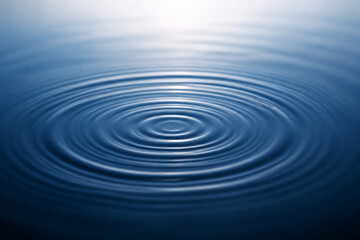 Fototapeta premium Close up of concentric ripples on a blue water surface, creating calm circular waves that spread outward. Concept for tranquility, reflection, and fluid motion in nature and atmosphere of calm seas