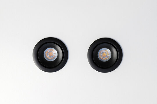 Black recessed ceiling spotlights on white