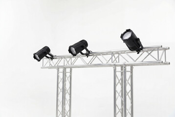 Obraz premium Three black stage lights mounted on silver truss over white background