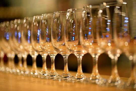 A row of neatly arranged empty wine glasses, inside the bar
