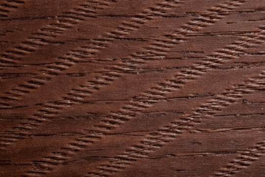 Dark brown wood surface with chiseled diagonal grain lines