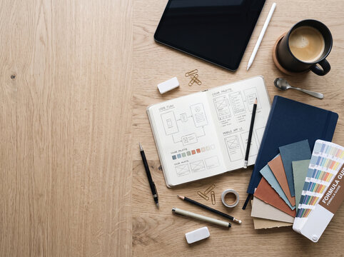 Designer's desk with UI wireframes, color swatches, and coffee