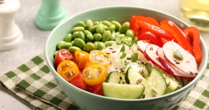 High fiber food. Tasty salad, rice, microgreen and seeds in bowl on grey textured table, closeup. Camera moving right