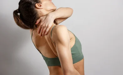 Woman holding her hand trapezius muscle and neck from behind in pain, upper back pain, muscle tension, posture problem, healthcare, physiotherapy and injury upper back muscle.  © Anastasia.photoyoga
