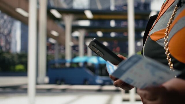 Traveler verifies a route with a printed bus ticket and smartphone; the tourist confirms journey details in the shuttle terminal before departure.