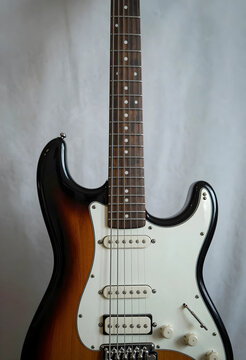 Electric guitar with sunburst finish and white pickguard, musical instrument for rock and blues music, the detailed view highlights the craftsmanship and components essential for sound production