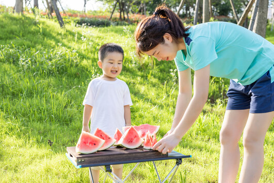 Mother and son sharing sliced watermelon outdoors on a sunny summer day