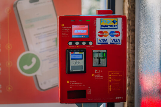 Red payment kiosk with touch screen and card reader displaying payment options in a public space in Bergamo, Lombardy