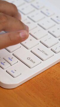Finger pressing shift key on white keyboard