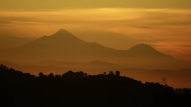 Pico de orizaba volcano at sunrise with fog and golden light
