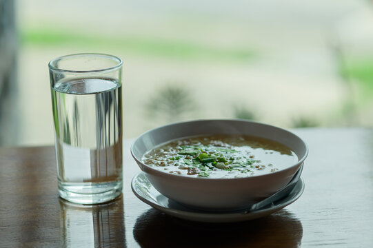 Freshly Served Bowl of Soup with Glass of Water on Wooden Table