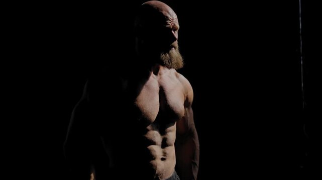A male bodybuilder poses in shorts, showing off his muscles. Close-up of his chest and abs.