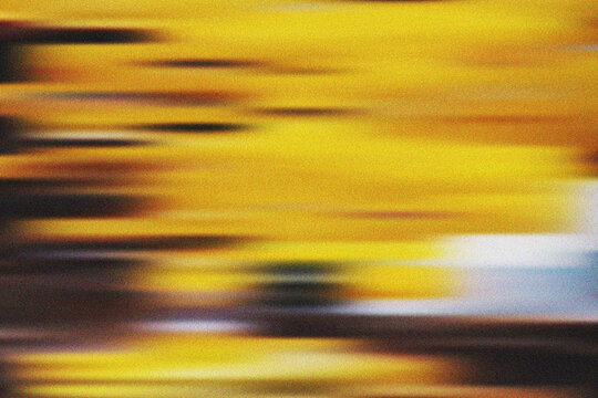 Warm golden abstract motion blur pattern showcasing vibrant yellow and orange tones with a distinctive grainy texture