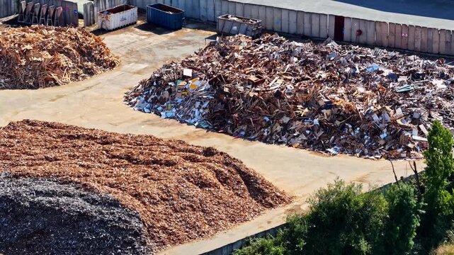 Massive mounds of sorted wood waste and scrap metal fill recycling yard with storage bins near Port of Bordeaux France