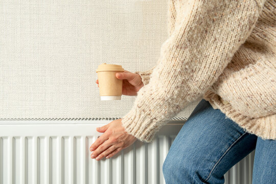 Heating season. Individual checks warmth of radiator while enjoying coffee. Home comfort concept
