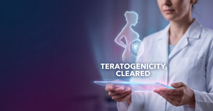 Doctor holding futuristic digital tablet displaying pregnancy protection hologram with teratogenicity cleared text in modern medical laboratory research environment setting