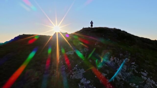 Hiker standing on Col d'Aubisque mountain peak with a spectacular lens flare sunrise