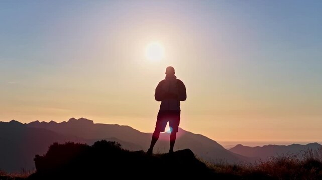 Hiker standing on a mountain peak at sunrise on the Col d'Aubisque, France