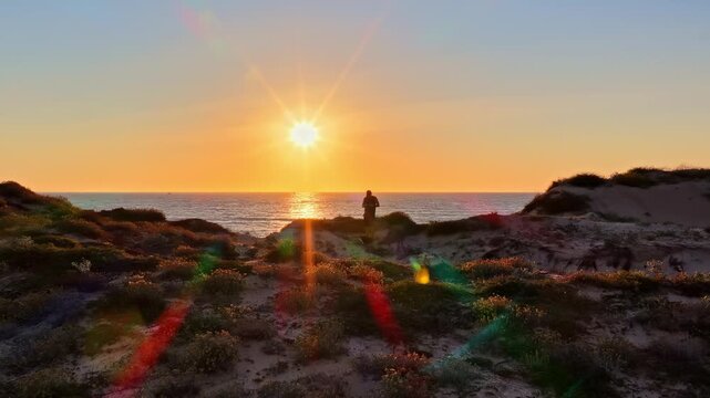 Person watching a beautiful sunset over the sea at Plage des Oc&eacute;anid from the top of sand dunes