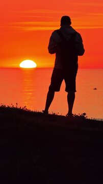 Man silhouetted against the sunset at the Dune du Pilat in France enjoying the moment