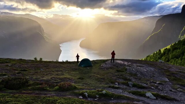 Two backpackers setting up a tent on a mountain summit above the Aurlandsfjord at sunrise