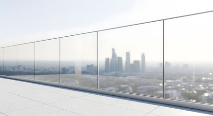 Fototapeta premium Modern glass balcony railing overlooking a hazy city skyline during the day.