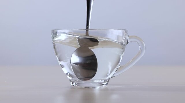 Metal Spoon Stirring Hot Water in a Transparent Glass Cup