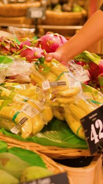 Customer Hand Picking Bagged Bananas in Thai Supermarket