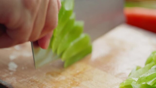 Close-up of thin slices of lettuce cut with kitchen knife on wooden cutting board
