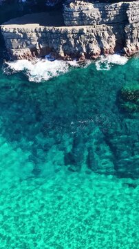 Aerial View of Turquoise Ocean Waves Crashing Against Coastal Cliffs