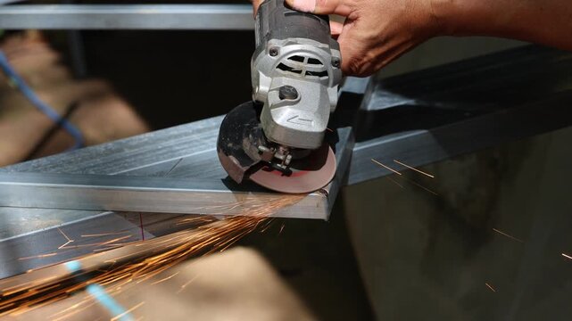 Angle grinder metal cutting spark steel hand tool industrial workshop grinding fabrication close up manual labor safety glove construction task աշխատանք