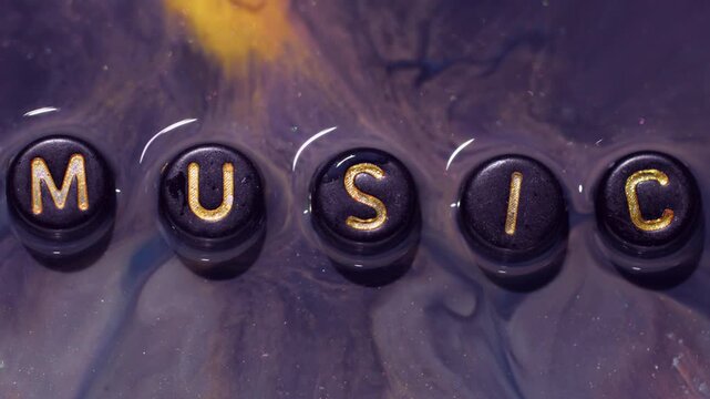 Ink text. Color fluid spill. Defocused yellow purple blue glitter music melody liquid black letters texture on abstract creative art background.