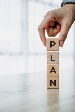 Close-up of a hand placing wooden letter blocks spelling PLAN. Business planning, strategy, goal setting, project management and growth concept with copy space.