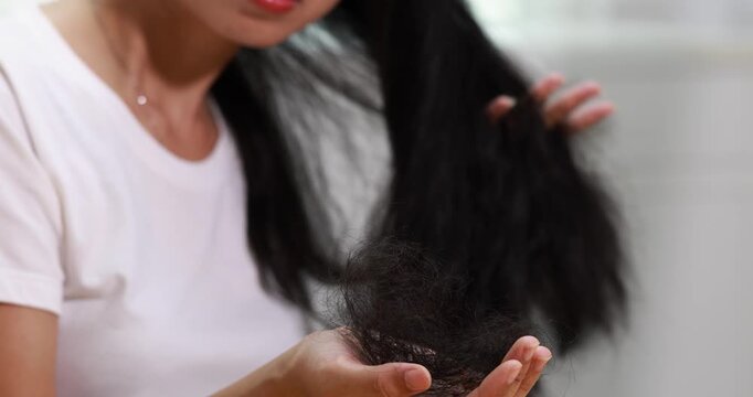 Young woman examining a large amount of hair in her hands, hair loss and concern