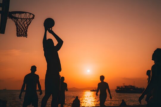 Silhouette of basketball player dunking at sunset near ocean