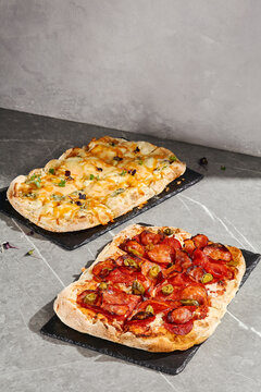 Roman pizza set with pepperoni and four cheese rectangular pizzas on black serving boards with bright copy space