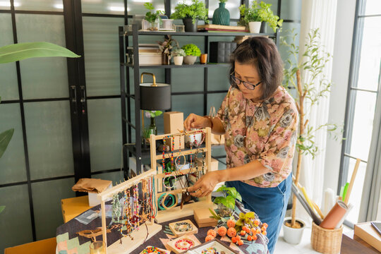 Mature Asian woman preparing handcraft jewelry for selling