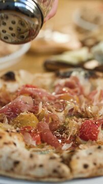 Hand Seasoning Gourmet Neapolitan Pizza with Spices in Restaurant
