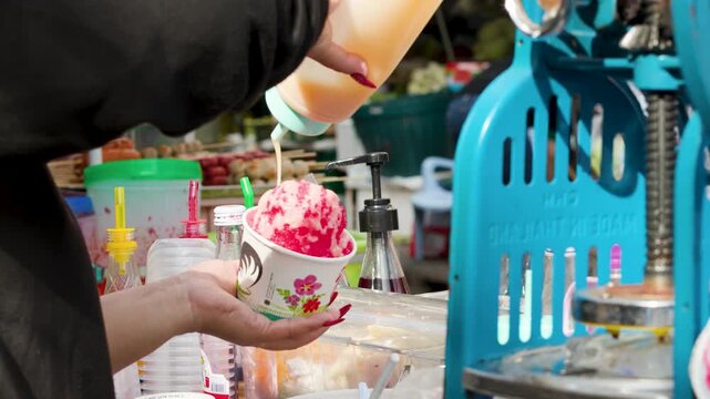 Vendor Pouring Condensed Milk Over Shaved Ice Dessert in Bangkok