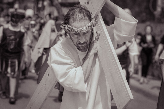 Actor representando a Jes&uacute;s cargando una cruz de madera durante la representaci&oacute;n del Viacrucis
