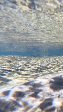 Underwater View of Sunlight Refracting on a Shallow River Bed