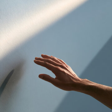 Hand reaches toward light, creating soft shadow