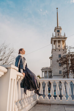 Woman city travel stylish woman sitting on a white stone balustrade near Sochi Marine Terminal with copy space