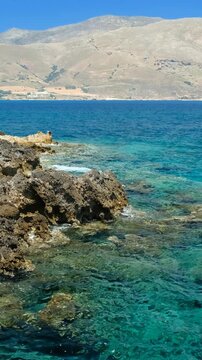 Vertical video of rocky shore of Crete Island with turquoise clear Mediterranean sea water. Greece.