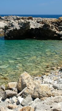 Vertical video of rocky shore of Crete Island with turquoise clear Mediterranean sea water. Greece